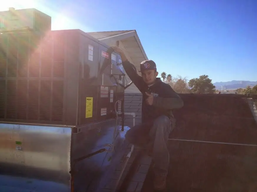 HVAC technician performing Air Duct Repair on a rooftop unit in Lower